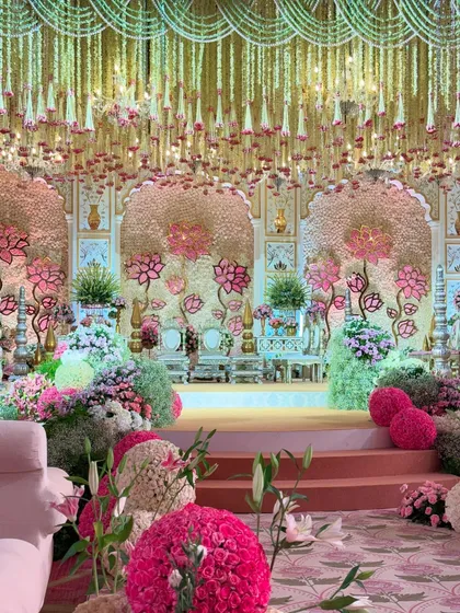A wide-angle view showcasing the grand scale of the mandap and the floral aisle. The soft pink seating and lush flower spheres complete this fairytale setting.