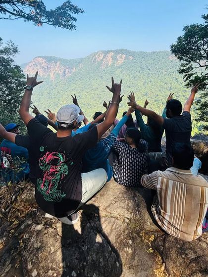 A group of trekkers celebrating at a viewpoint on the Narasimha Parvatha trail, with the Agumbe hills in the background.