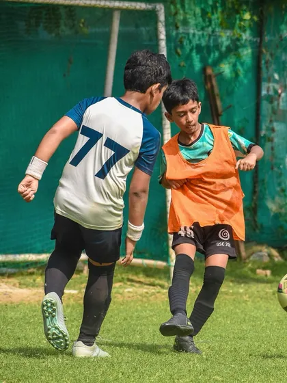 Two young players challenge for the ball, showing great determination and focus.