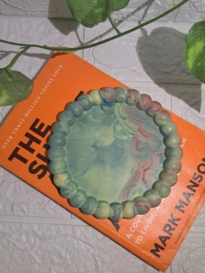 A styled shot of our Aurora bubble tray, placed on a book with a plant in the background.