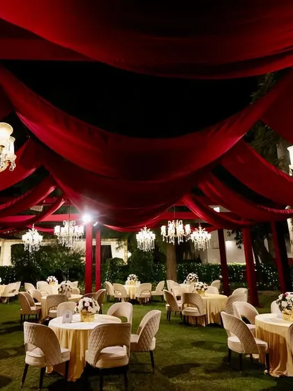Another perspective of the grand red-draped reception, showing the elegant guest tables and comfortable lounge seating areas.