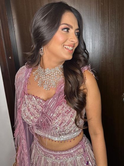 A happy bride at her reception. The soft pink and lavender tones in her makeup beautifully echo the colors in her feathered lehenga.