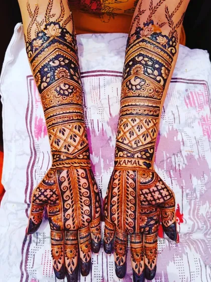 A beautiful example of full-arm bridal mehndi with heavy, intricate work. The design uses a mix of traditional jaal patterns and bold floral motifs to create a rich and dense look, perfect for a royal wedding theme.