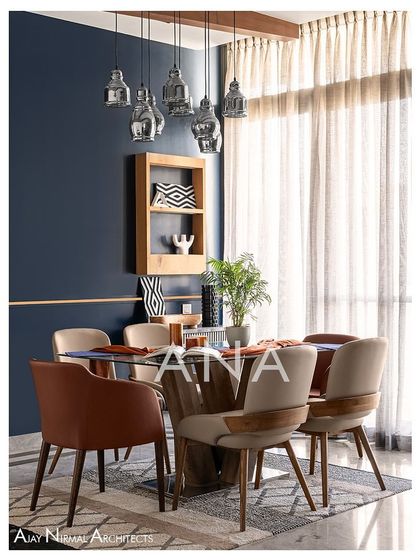 The dining area of Apartment 704, with its mix of chair styles and colors, creates a dynamic and inviting space. The large window allows for plenty of natural light, illuminating the rich material palette.
