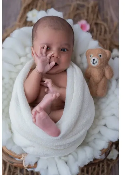 A moment of quiet curiosity. This baby, nestled in a basket with his teddy bear, brings his hand to his mouth in a classic newborn gesture. These are the authentic, unscripted moments I aim to capture.