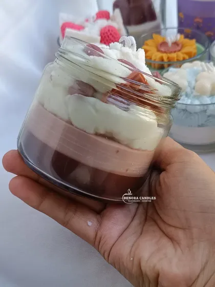 A hand-held view of the coffee dessert jar candle, showing its size and intricate layers.