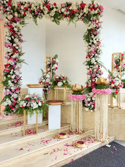 A closer view of the floral arch and decorative pedestals, showcasing the mix of pink and white flowers and hanging jasmine strings.