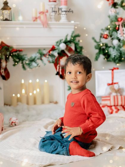 A sweet smile by the warm glow of the fireplace. This cozy Christmas setup creates a classic and heartwarming holiday portrait.