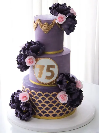 Celebrating 75 glorious years with a cake that’s fit for royalty. This three-tiered masterpiece features a regal purple ganache finish, intricate gold stenciling, and a cascade of handmade sugar peonies and roses. The top two tiers were a delicate pistachio rose, with a rich chocolate cake for the base.