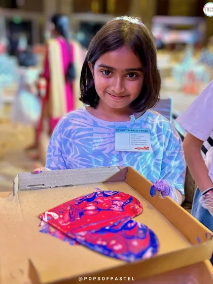 A young artist proudly presents her heart-shaped fluid art creation. We teach techniques like using silicone oil to create those amazing cell effects.