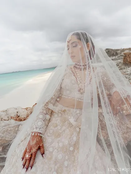 A moody and ethereal bridal portrait of Dhwani on the coast of Tanzania. The overcast sky and the gentle drape of her veil over the cliffs created a dramatic and beautiful scene.
