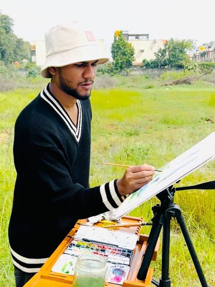 A focused shot of me painting the rural scene, concentrating on the details of the landscape.