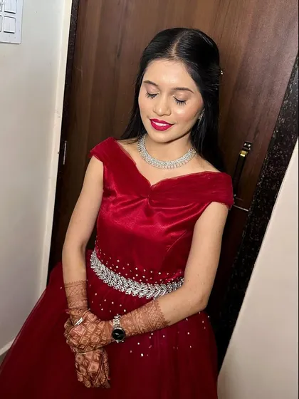 A classic reception look in a beautiful red gown. The makeup is glamorous with a bold red lip, and the hair is styled in soft, open waves.