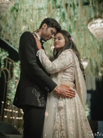 A romantic portrait of the couple at their reception, surrounded by hanging floral decor and chandeliers.