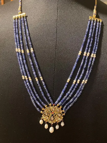A view of the necklace as worn, showing how the five strands of sapphire beads drape elegantly. This piece combines traditional motifs with timeless style.