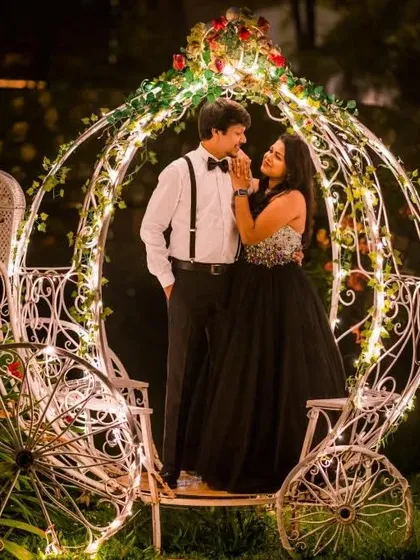 Live out your fairytale dream with a pre-wedding shoot featuring this elegant black ball gown. Paired with a classic suit and a romantic, lit-up carriage prop, this rental outfit combination creates truly magical and timeless photographs.