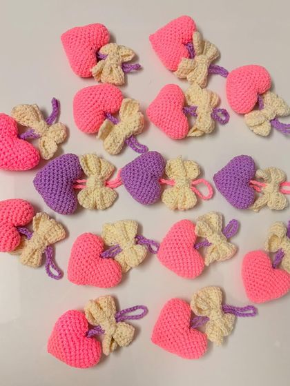 These heart-shaped bag hangings are a lovely accessory. Each pink heart is paired with a little cream-colored bow, making them a sweet and charming gift.