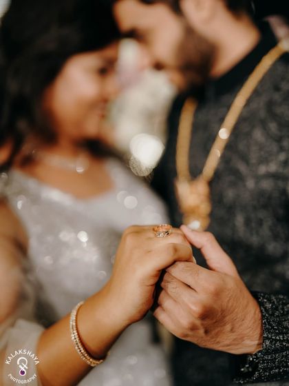 A close-up shot focusing on the couple's hands and the engagement ring.