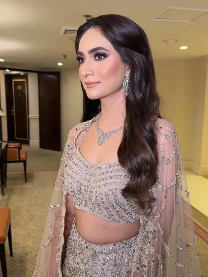 A side profile showing the soft waves and the flawless finish of the makeup. The highlighter gives her skin a beautiful, ethereal glow.