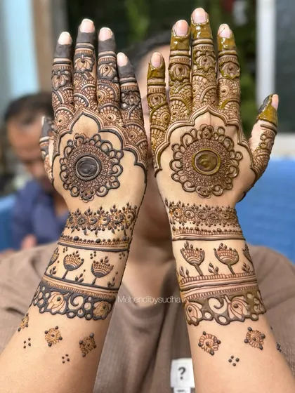 A full view of the engagement mehendi, showcasing the beautiful mandala on the palms and the delicate floral bands on the forearms.