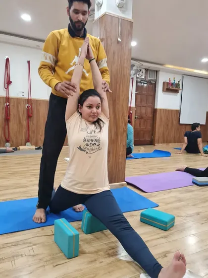 I am helping a student find the right alignment in her supported split. Hands-on adjustments are key to ensuring students practice safely and effectively.