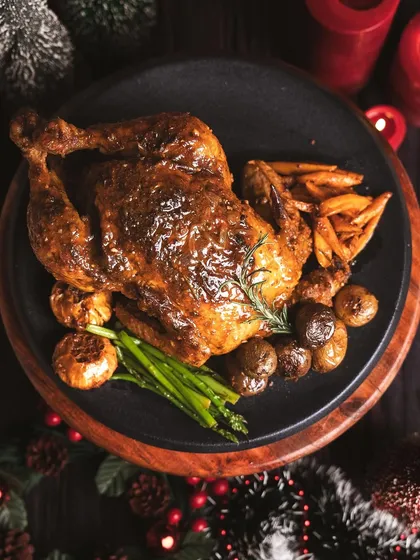 A classic holiday centerpiece. This perfectly roasted chicken, served with roasted potatoes, carrots, and asparagus, is a wholesome and delicious meal for your Christmas gathering.