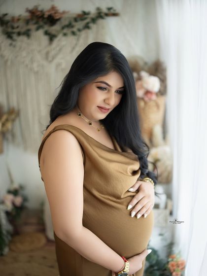 A soft and contemplative portrait by the window. The natural light creates a beautiful, gentle mood, perfect for capturing the quiet moments of pregnancy.
