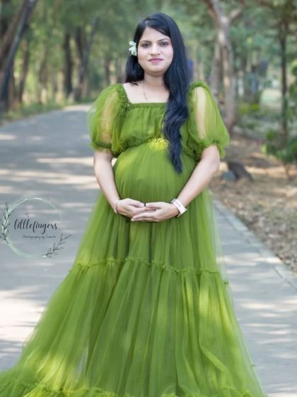 A graceful solo portrait on a park pathway. The soft, puffy sleeves of the green gown add a touch of romance to this mom-to-be's look.