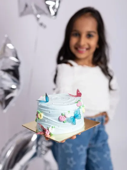 A close-up of the beautiful butterfly-themed cake, with the birthday girl smiling proudly in the background. It's all in the details!