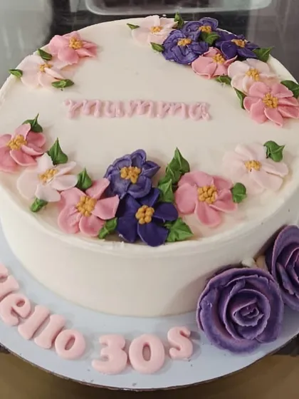 A "Hello 30s" cake with beautifully piped buttercream flowers in shades of pink and purple.