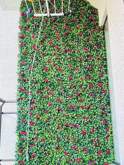 This balcony wall is covered in our artificial boxwood panels dotted with small red flowers. It's a great option for adding a pop of color that remains vibrant in all seasons without fading.