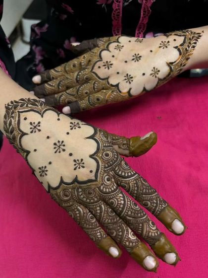 I love the elegance of negative space in mehendi. This Pakistani-inspired design features a scalloped border filled with tiny floral butis, leaving the center of the hand open for a striking contrast.