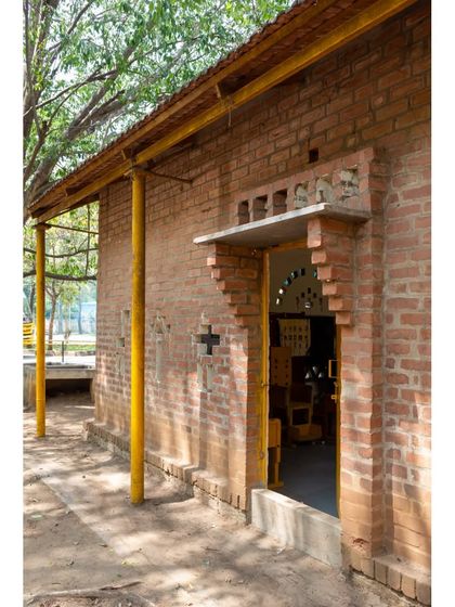 The entrance to the Spastic Society classroom, showing the detailed brickwork and a small canopy. The building is fully accessible for children using wheelchairs, a core part of its inclusive design.