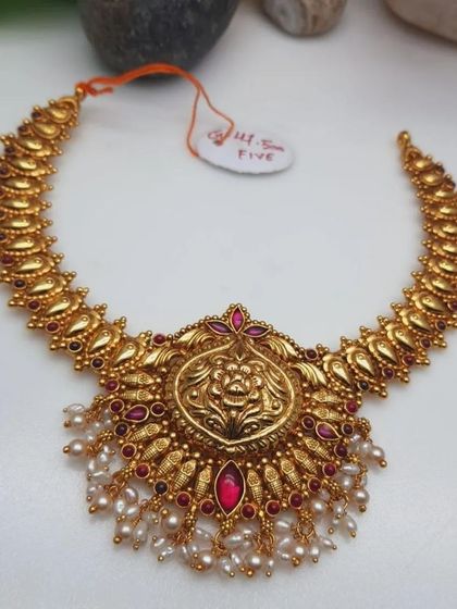 A beautiful temple necklace with a large goddess pendant. The necklace is made from 92.5 silver with gold plating and is adorned with ruby-colored stones and pearl drops.