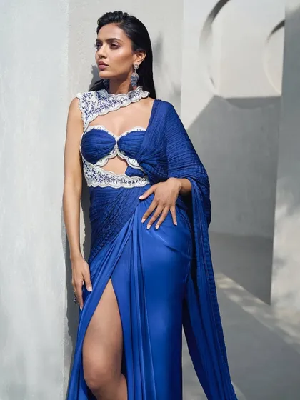 A pre-draped sari in a striking active blue hue, crafted from crushed fabric and elevated with delicate pearl embellishments. A statement in motion for the contemporary muse.