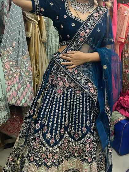 A deep blue velvet lehenga with detailed floral embroidery in shades of pink and silver. This outfit offers a unique and rich alternative to traditional red, perfect for a winter wedding or reception.
