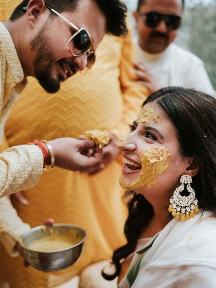 A friend playfully applying Haldi to the bride's face. These are the fun, candid interactions that make the celebration memorable.