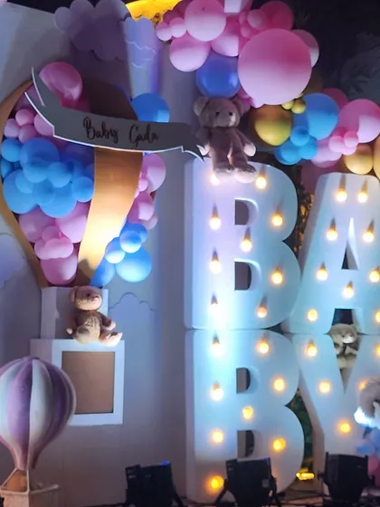 This whimsical baby shower featured large marquee letters, teddy bears nestled in pastel balloon clouds, and a custom hot air balloon prop, creating a dreamy and joyful atmosphere.