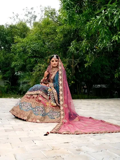 A full-length bridal portrait that showcases the grandeur of the lehenga and the elegance of the bride. Shot outdoors in a beautiful garden, this photo highlights the complete bridal look in a natural, regal setting.