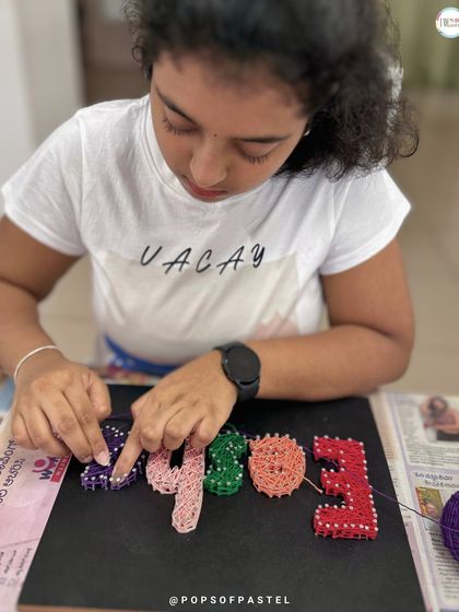 The weaving process is where the magic happens. This artist is carefully wrapping string to fill in the letters of her name.