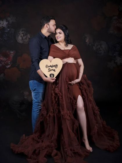 Announcing the big news with a sweet, heart-shaped "Coming Soon" sign. This is a classic couple's pose that is full of warmth and excitement.