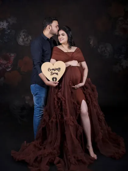 Announcing the big news with a sweet, heart-shaped "Coming Soon" sign. This is a classic couple's pose that is full of warmth and excitement.