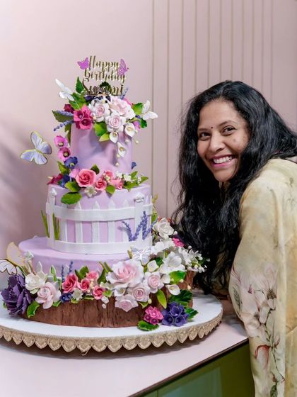 A smile of pride next to our 40kg creation. This cake was a true labour of love, and we are so happy with how this floral and butterfly-themed masterpiece turned out.