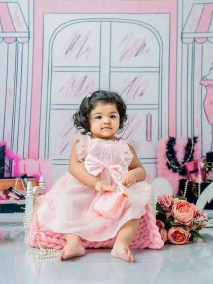 Another angle from the first birthday Barbie shoot, showing her sitting elegantly on a pink cushion amidst flowers and pearls.