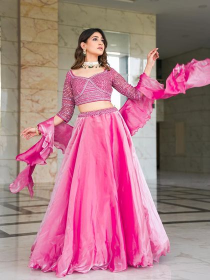 A gorgeous rose pink lehenga with a stone-encrusted blouse and dramatic ruffled bell sleeves. This is a fun, fashionable, and vibrant choice for a mehendi or sangeet party.