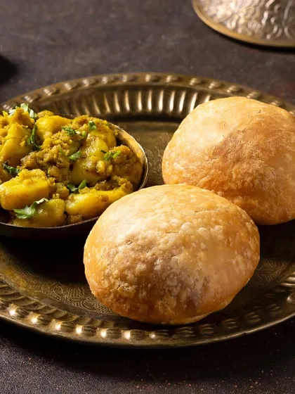 Fluffy kachoris served with a side of aloo sabzi. This shot for Chhappan Bhog uses traditional brassware to evoke an authentic, comforting feel.