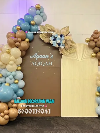 A stylish and modern setup for an Aqiqah ceremony. The earthy tones of brown and dusty blue balloons, paired with dried palm leaves and dual arched backdrops, create a sophisticated, bohemian-inspired look.