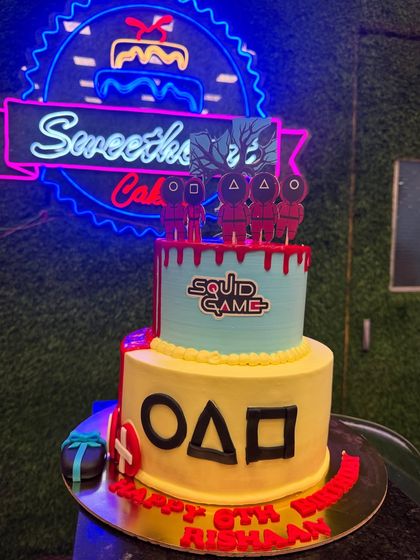 Another view of the Squid Game cake, highlighting the detailed toppers and the two-tier design. This cake is perfect for a themed party and is sure to be a conversation starter.