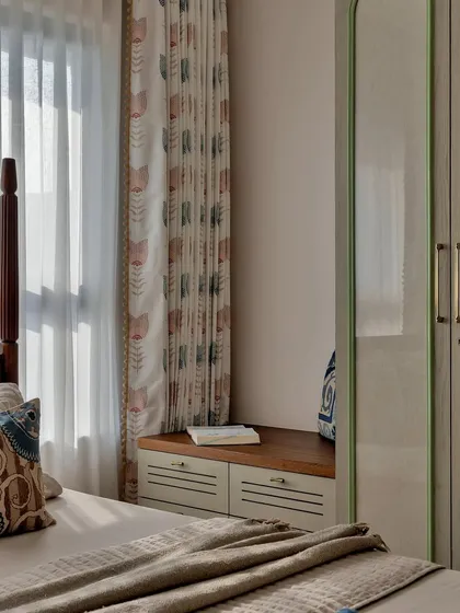 A cozy window seat provides extra storage and a perfect spot for reading. The patterned curtains add a touch of color and personality to this charming corner.