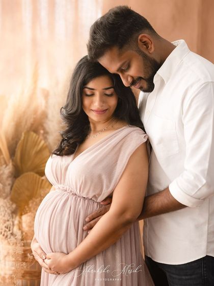 A warm and gentle maternity portrait. The soft lighting and pastel colors create a peaceful and romantic mood for the expecting couple.